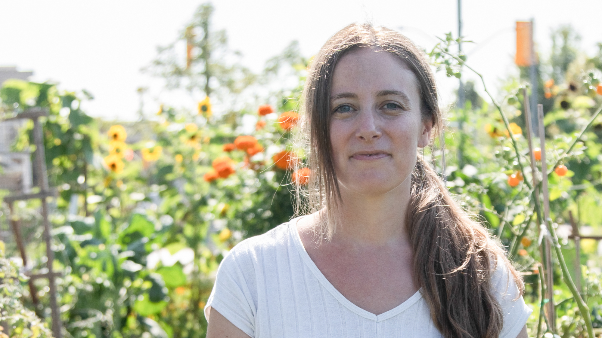 Britt, Executive Director of United Way-funded Ecosource, stands in front of blossoming flowers and tomato vines at one of the agency's community gardens.