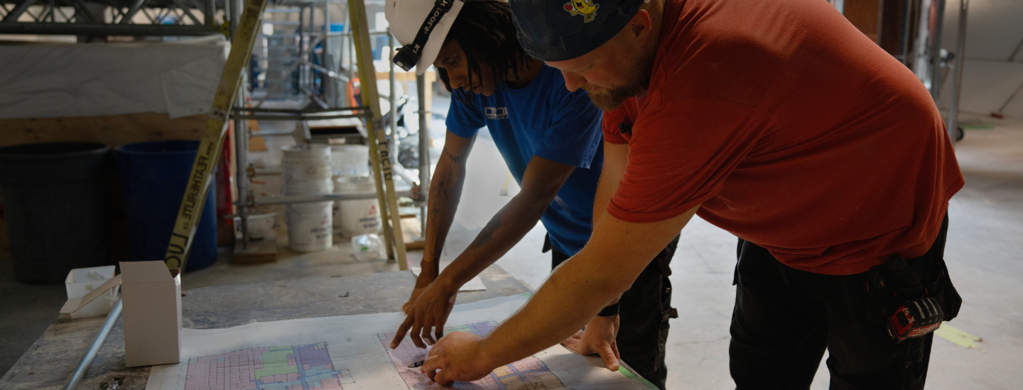 Construction workers looking at plans for a community hub