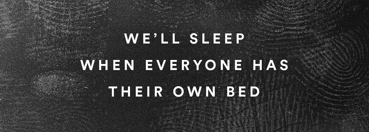 A black background covered in thumbprints with the words ‘We’ll sleep when everyone has their own bed’ written in blue overtop. 