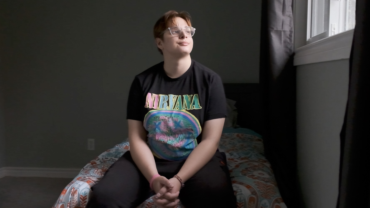 Serpil, a United Way program participant, sits on a bed, looking out the window.