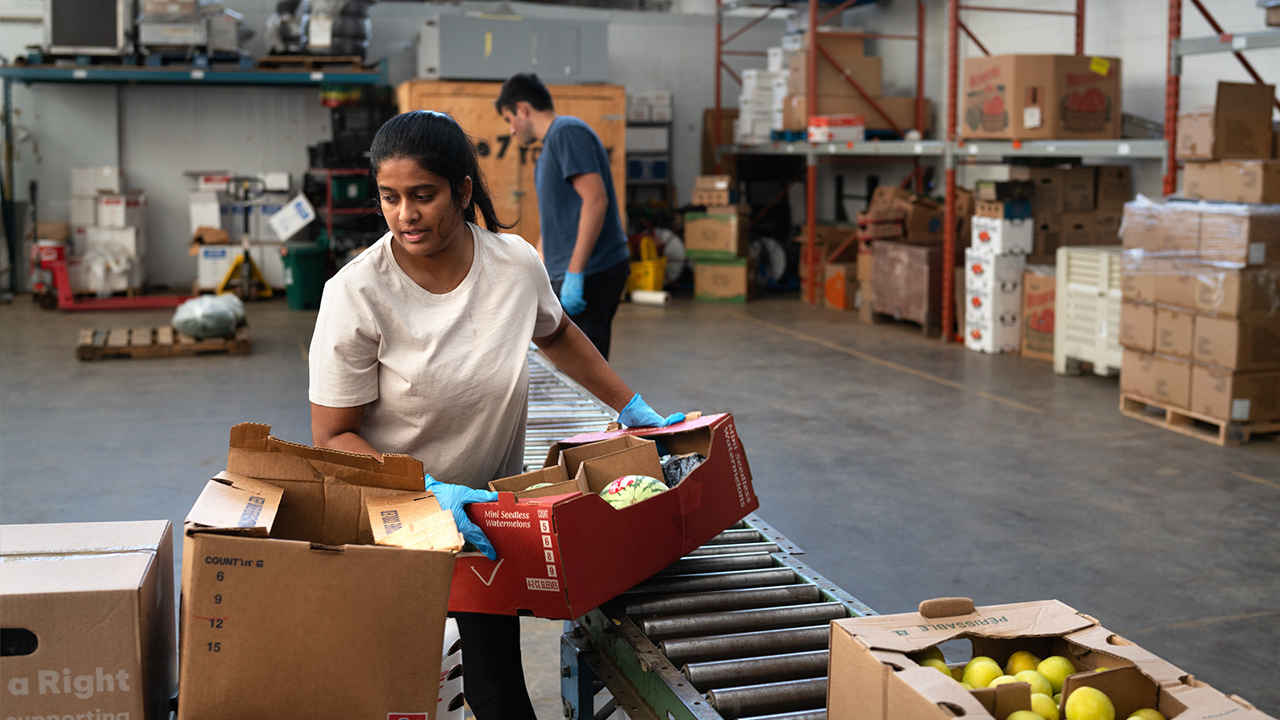 A woman moves boxes of food at a United Way funded food bank