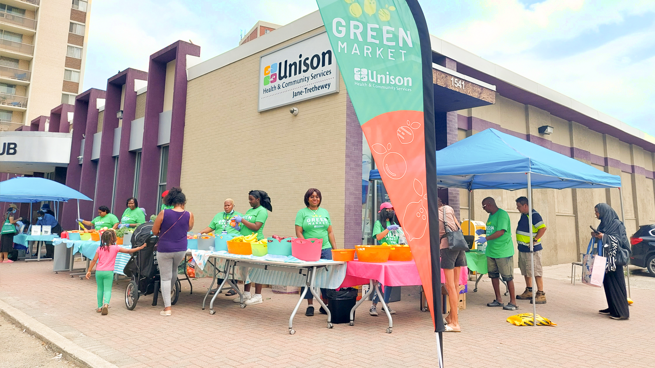 People gathered around tables at a community event outside the Jane Street Hub