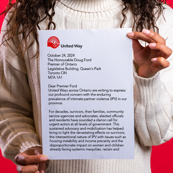 A person holding up a paper copy of the letter to the Ontario government from United Ways across Ontario about intimate partner violence.