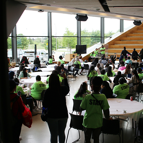 A room full of people in bright yellow shirts sitting around tables.