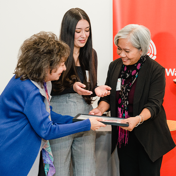 A woman is presented with an award by two other women at the Bhayana Family Foundation Awards.