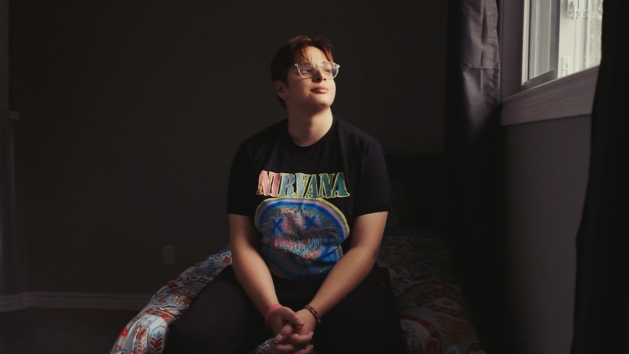 A young person named Serpil, in housing from 360°kids, looks out a window. 