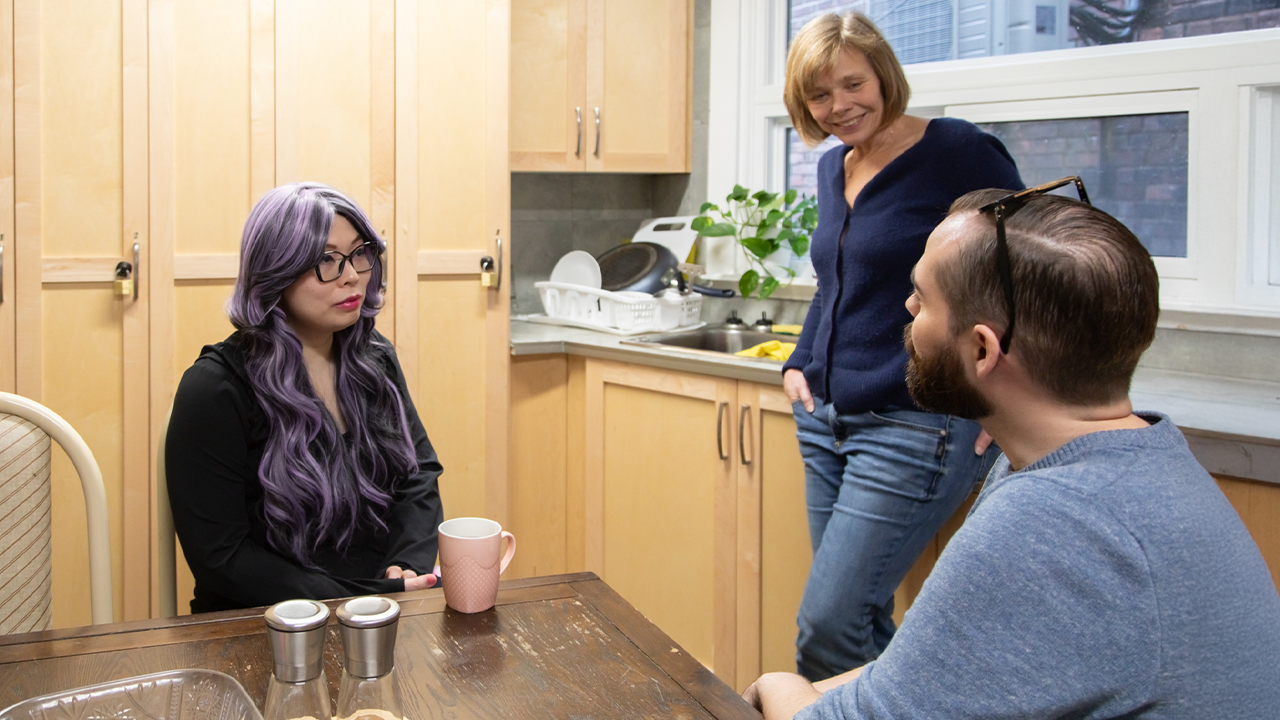 A woman named Diana sitting at a table speaking to two people from LOFT Community Services.