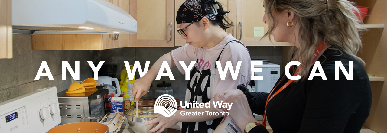 Two people stand in a kitchen preparing food with the words ‘Any Way We Can’ and the United Way Greater Toronto logo written on top in white. 